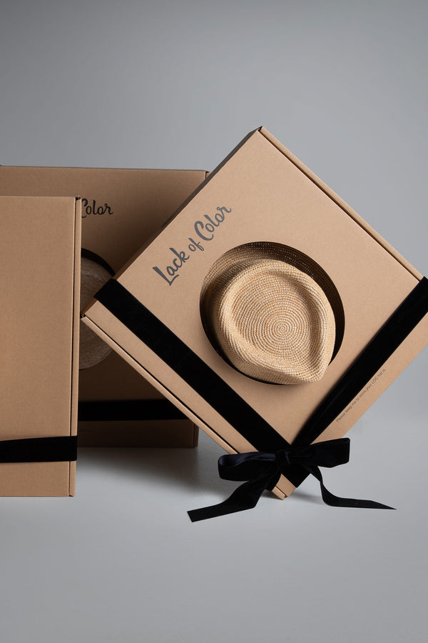 Two gift boxes with a hat, wrapped in black ribbon, featuring 'Lack of Color' branding.