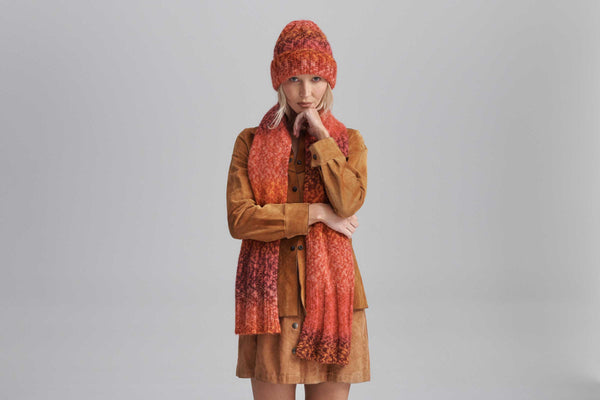Model wearing Kai Scarf in Flame color with matching hat, showcasing rib detail.