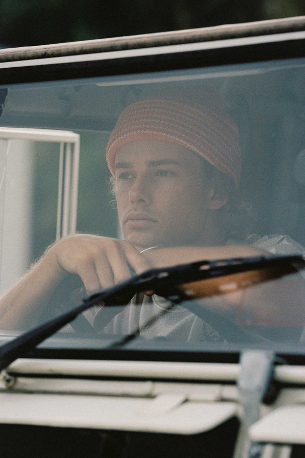 A young man wearing an orange striped beanie, sitting in a vehicle.
