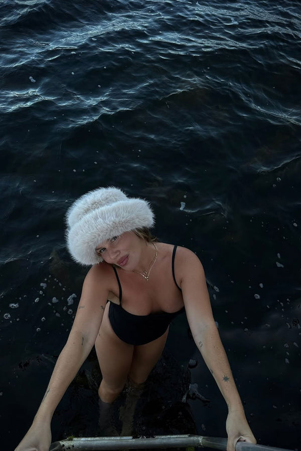 Model wearing Snuggle Bucket hat in water, showcasing its style and fit.