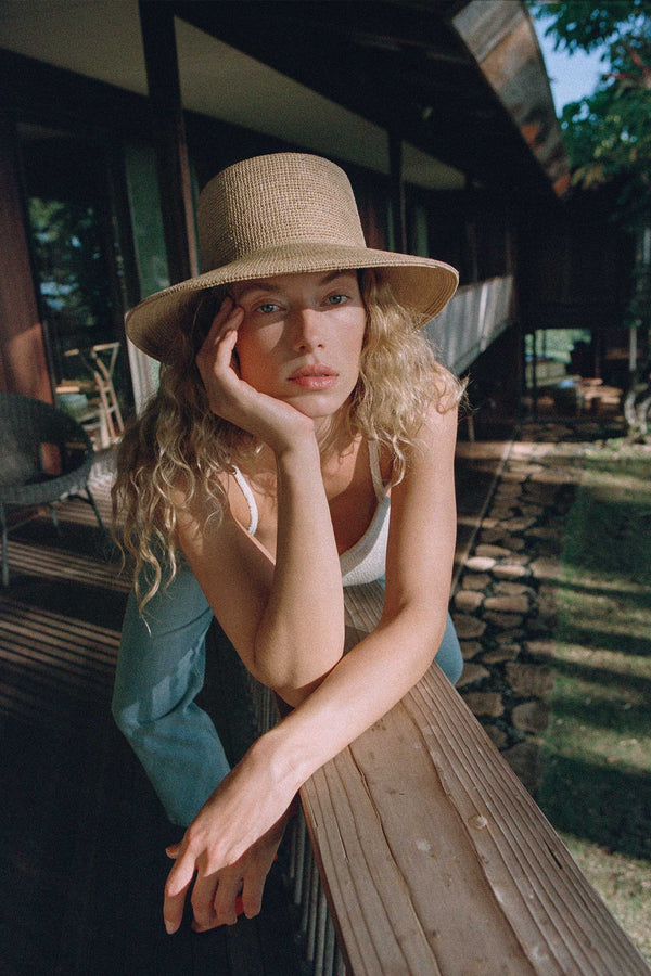 Model wearing The Inca Bucket straw hat, showcasing its natural color and style.
