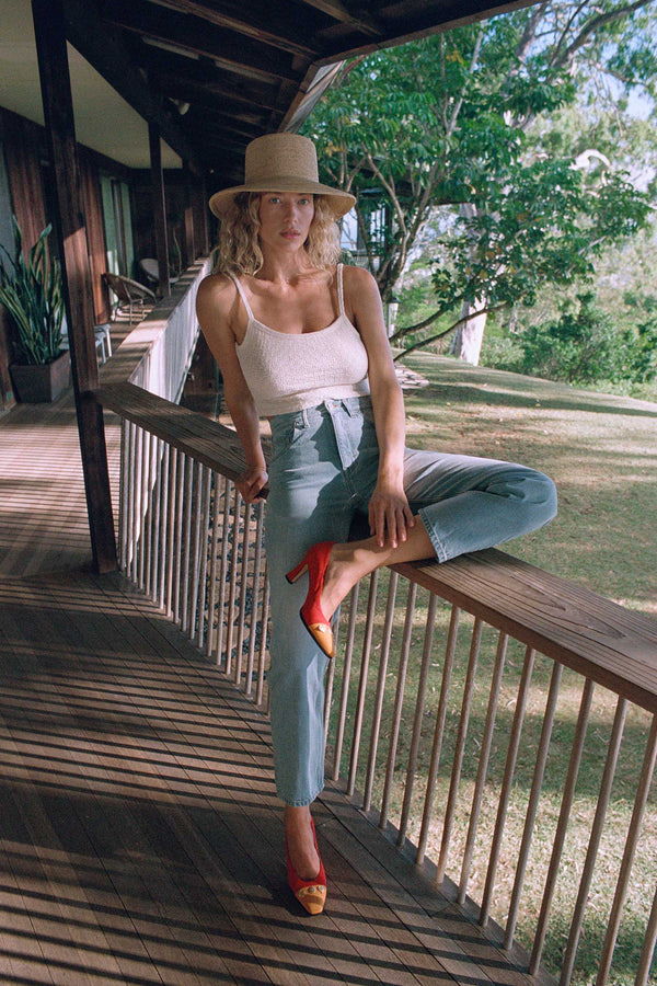 Model wearing The Inca Bucket straw hat, standing on a porch with a natural background.