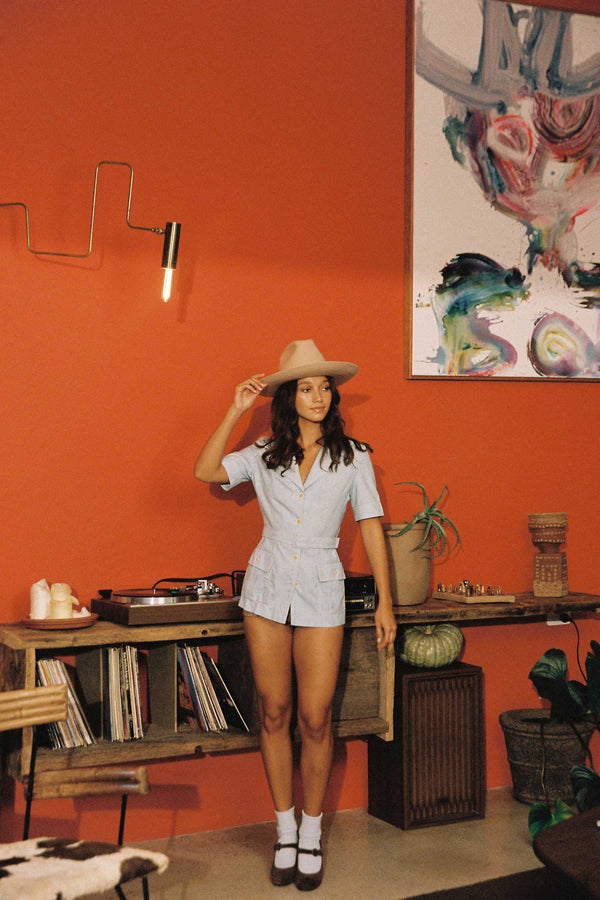 Model wearing a Cassidy Western wool felt cowboy hat in beige, standing in a colorful room.