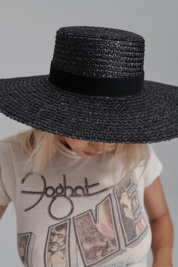 Mira Wide Boater in black wheat straw, featuring a wide brim and black faux suede ribbon.