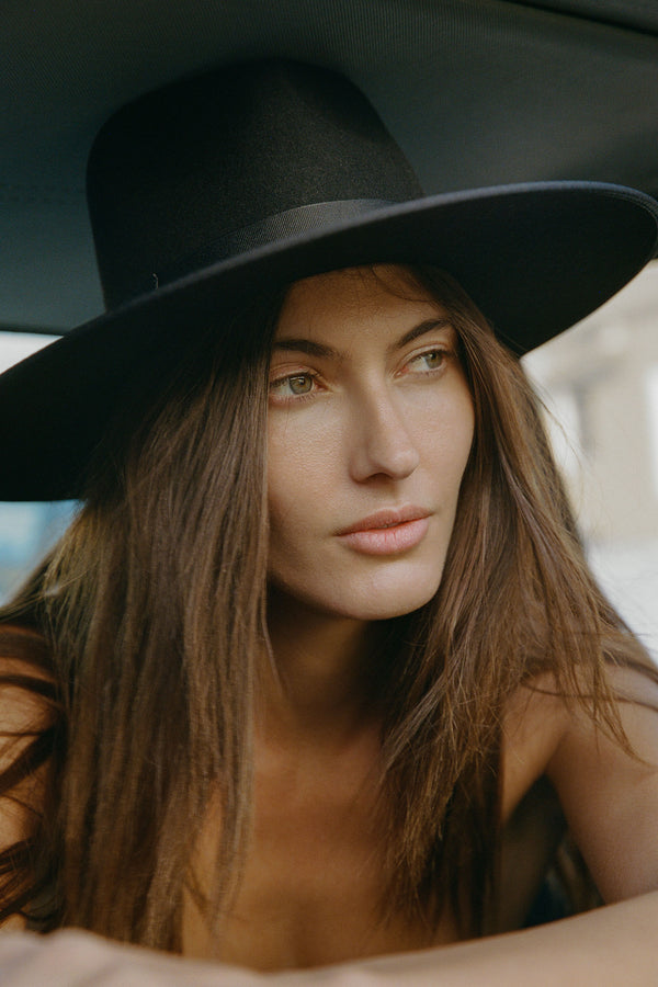 Model wearing the Noir Rancher wool felt fedora hat in black, showcasing its design and fit.